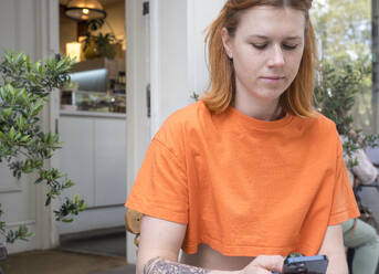 Redhead woman using smart phone at sidewalk cafe - AMWF01685