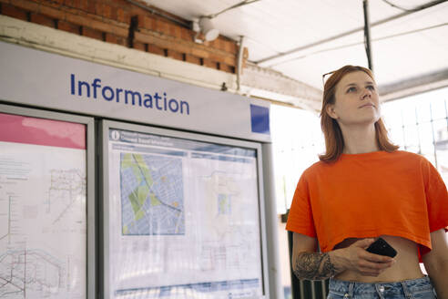 Nachdenkliche Frau mit Mobiltelefon in einer U-Bahn-Station - AMWF01696