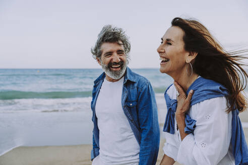 Cheerful senior couple walking by sea at beach - OIPF03390