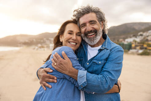 Glückliches älteres Paar, das sich am Wochenende am Strand umarmt - OIPF03396