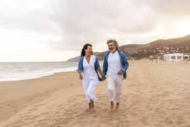 Glückliches heterosexuelles Paar, das am Strand spazieren geht - OIPF03418