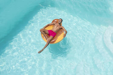 Glücklicher junger Mann auf aufblasbarem Schwimmer im Pool liegend - VRAF00139