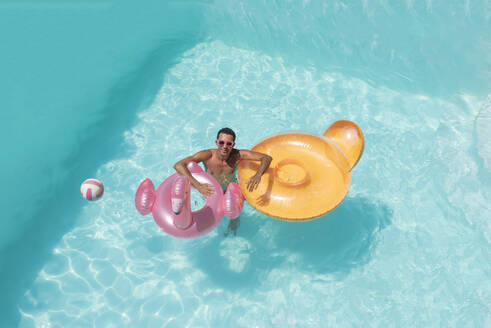 Lächelnder Mann mit aufblasbaren Schwimmern im Pool - VRAF00142