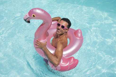 Lächelnder Mann mit aufblasbarem Schwimmring im Pool - VRAF00143