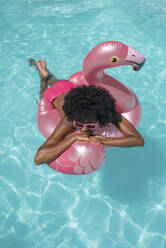 Frau entspannt sich auf einem Schwimmkörper im Pool - VRAF00156