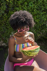 Young woman drinking watermelon juice with straw on sunny day - VRAF00182