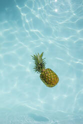 Auf dem Wasser schwimmende Ananas im Schwimmbad - VRAF00187