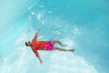Junger Mann mit Sonnenbrille beim Schwimmen im Wasser - VRAF00188