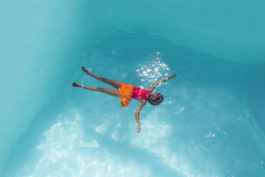 Junge Frau mit Sonnenbrille beim Schwimmen im Pool - VRAF00189