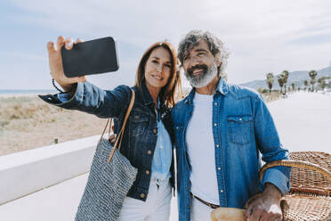 Happy senior man and woman taking selfie near beach - OIPF03433