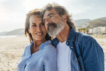 Nachdenklicher älterer Mann mit lächelnder Frau am Strand am Wochenende - OIPF03466