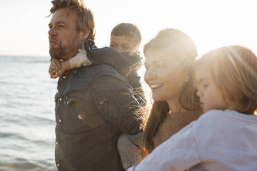 Parents carrying children by sea at beach on weekend - JOSEF20612