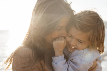 Happy mother carrying daughter at beach on holiday - JOSEF20616