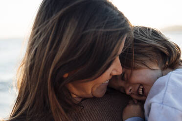 Happy mother and daughter spending leisure time at beach - JOSEF20641