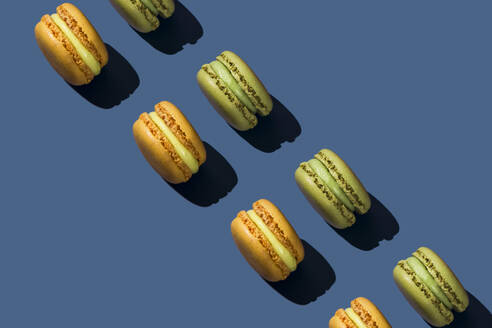 Green and yellow macaroons arranged on blue background - FLMF01016
