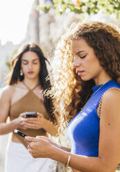 Young girlfriends using smart phones - PBTF00204