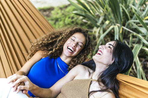 Happy lesbian couple laughing in hammock - PBTF00229