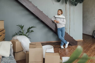 Young man standing by staircase at home - VPIF08537