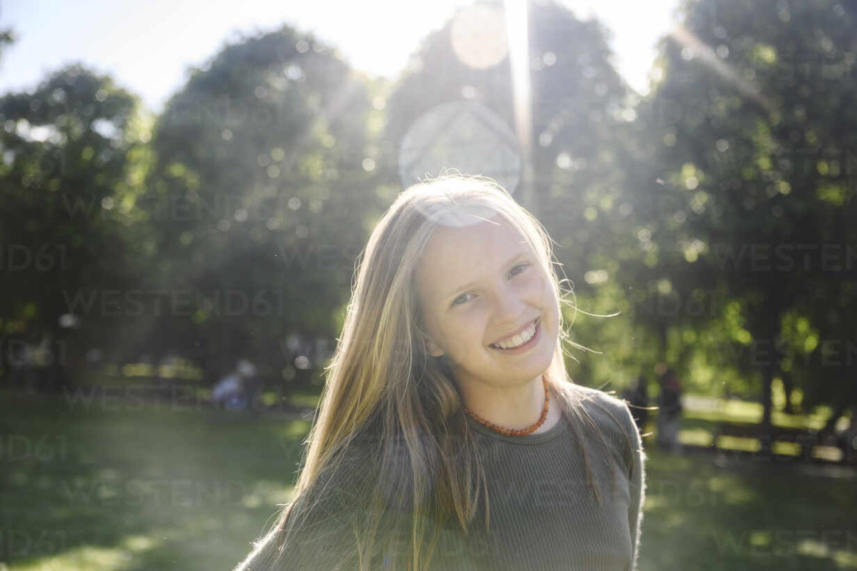 Smiling girl in park on sunny day stock photo