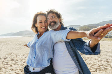 Happy senior couple enjoying vacations at beach on sunny day - OIPF03470