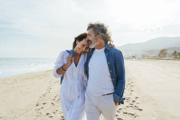 Loving senior couple walking at beach on sunny day - OIPF03484