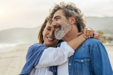 Smiling woman embracing man at beach - OIPF03508