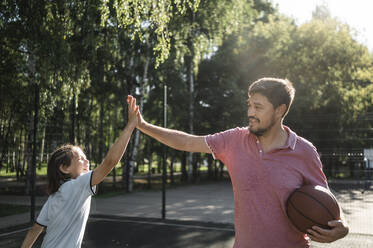 Vater mit Basketball gibt seinem Sohn im Gerichtssaal ein High-Five - ANAF02059