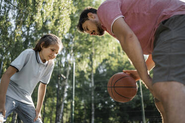 Father teaching son to dribble basketball - ANAF02061