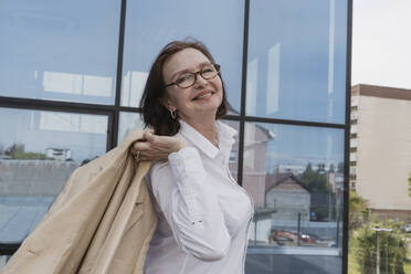 Lächelnde Geschäftsfrau mit Blazer vor einem Bürogebäude - OSF02066