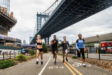 Multi-ethnic group of runners training outdoors - Sportive people running on the street of Manhattan, concepts about sport and healthy lifestyle - DMDF03872