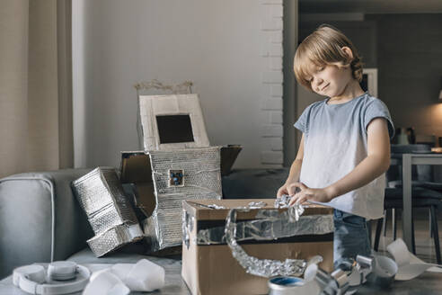 Smiling boy making astronaut suit at home - EVKF00001