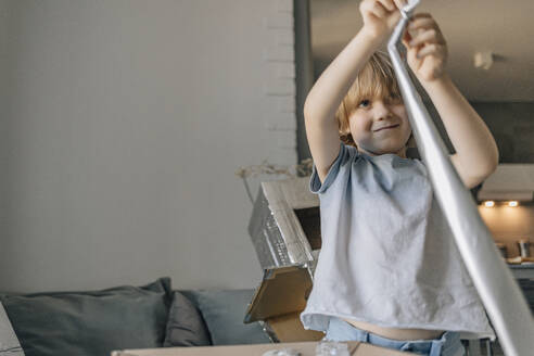 Boy with foil paper making hand made astronaut suit at home - EVKF00005