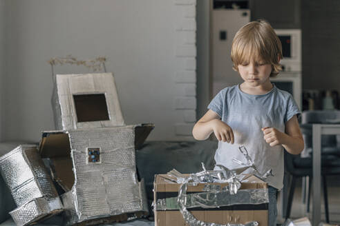 Boy making astronaut robot suit with foil paper at home - EVKF00009