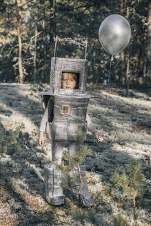 Junge mit silbernem Luftballon im Astronautenanzug im Wald - EVKF00017