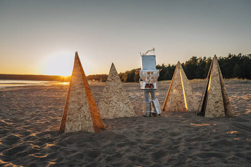 Junge im Astronautenanzug geht in der Nähe einer futuristischen Struktur am Strand spazieren - EVKF00031