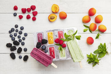 Raw berry fruits and homemade popsicles on wooden surface - GWF07897