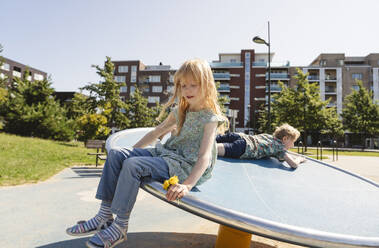Brother and sister playing on playground on sunny day - IHF01611