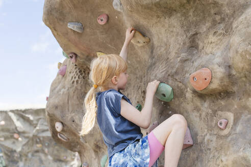 Mädchen klettert auf dem Spielplatz an der Felsenwand - IHF01618