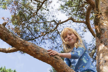 Smiling blond girl on tree branch - IHF01640