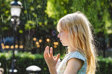 Blondes Mädchen genießt das Wasser eines Springbrunnens im Park - IHF01654