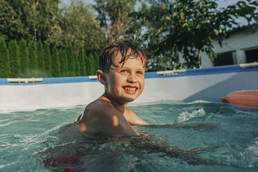 Happy boy swimming in wading pool - VSNF01379