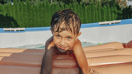 Niedlicher Junge mit Schwimmflügeln genießt den Sommer im Hinterhof - VSNF01380