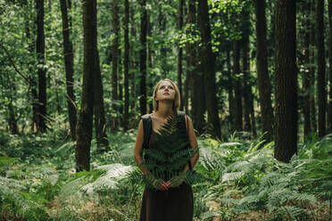 Frau mit Farnblatt erkundet Wald - VSNF01385