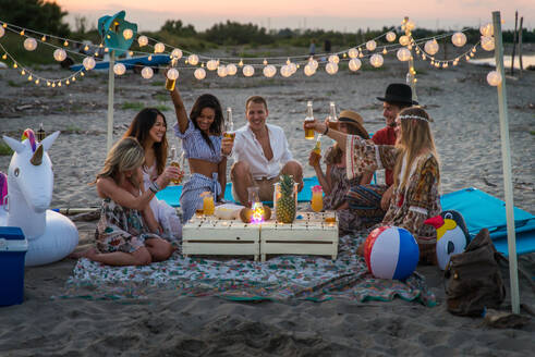 Eine Gruppe von Freunden macht ein Picknick am Strand - Glückliche junge Leute im Sommerurlaub am Strand - DMDF04026