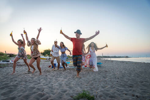 Fröhliche Gruppe von Freunden beim Feiern und Spaß haben am Strand - Junge Leute im Sommerurlaub - DMDF04041