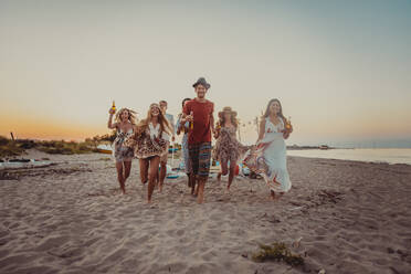Fröhliche Gruppe von Freunden beim Feiern und Spaß haben am Strand - Junge Leute im Sommerurlaub - DMDF04048