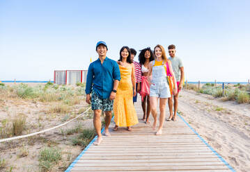 Multiethnic group of young happy friends bonding outside, having fun on summertime vacation - Multicultural cheerful people with summer clothes enjoying summer holidays, concepts about youth, friendship and positive emotion - DMDF04064