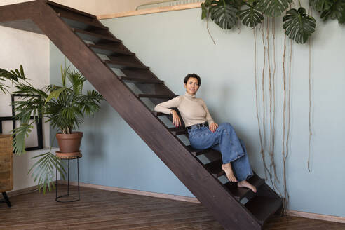 Smiling woman sitting on staircase - VPIF08548