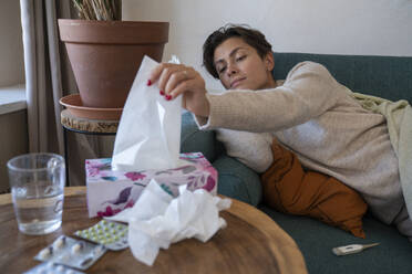 Sick woman taking out tissue from box at home - VPIF08640