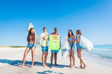 Eine Gruppe freiwilliger Umweltschützer hält nach der Müllsortierung Plastiksäcke in der Hand - Freunde säubern den Strand und sammeln Plastik, um das Leben im Meer zu retten - DMDF04082